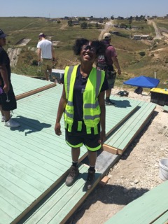 A Colorado Uplift student smiles broadly while standing on a foundation of service and leadership while building homes in Tijuana